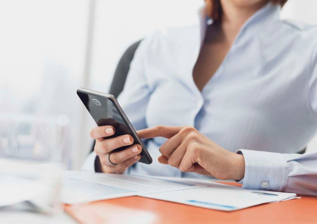 Corporate businesswoman using financial apps on her smartphone